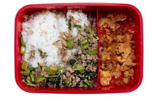 Bright red plastic lunch box with food compartments. Food of Stir-fried minced pork with basil mixed with Morning glory and cut into pieces. Divide in half of Stir-fried Preserved Radish with Egg. photo
