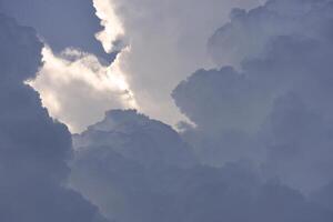 Blue-white cumulus clouds in the rays of the sun. Thunderstorm clouds. photo