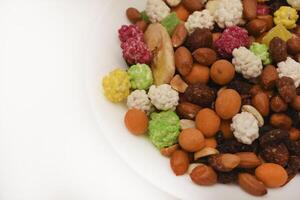 Sweet assorted nuts and dried fruits in a plate on a white background. photo