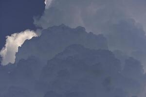 Blue-white cumulus clouds in the rays of the sun. Thunderstorm clouds. photo