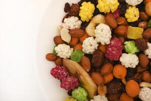 Sweet assorted nuts and dried fruits in a plate on a white background. photo