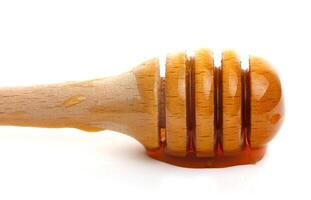Honey dripping from a wooden dipper on a white background isolate photo