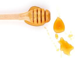 Honey dripping from a wooden dipper on a white background isolate photo