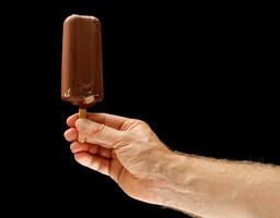 Chocolate ice cream on a stick in hand photo