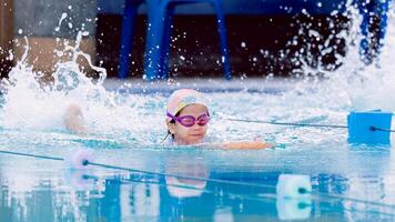 Asian child girl are enjoying a swim in the pool on sunny summer day, surrounded by fun and action. Kid wearing a swimsuit uses a foam pad to practice swimming in a swimming pool, happily and smiling. photo