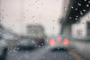 Rain drops on car window and lights. the bokeh image made with traffic and electric lights through the window of car on a rainy day. photo