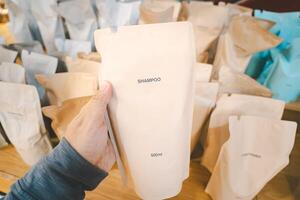 Hand holding Refill packet. Zero waste. Reuse reduce recycle concept. refill liquid soap, shampoo and other products. Plastic packaging for refill pouch in store. photo