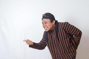 Portrait of friendly Asian man in javanese cloth with blangkon hat inviting someone to come in the most polite manner. Isolated image on white background photo