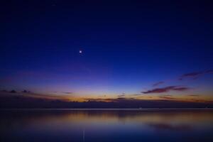The moon and first star on sky at the lake in the twilight after sunset. photo