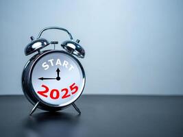 Start text and 2025 on white alarm clock on black table with copy space for preparation of Merry Christmas and Happy new year concept. Start new business, Start up, New trend to next year concept. photo