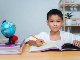 Student learning study reading book while sitting at home. Education, Childhood, People, Homework and school concept. Student boy with book writing to notebook at home. photo