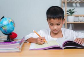 Student learning study reading book while sitting at home. Education, Childhood, People, Homework and school concept. Student boy with book writing to notebook at home. photo