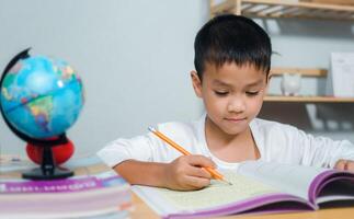 Student learning study reading book while sitting at home. Education, Childhood, People, Homework and school concept. Student boy with book writing to notebook at home. photo