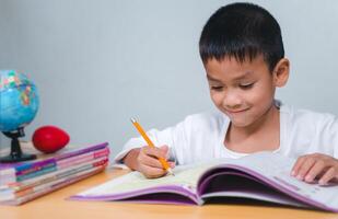Student learning study reading book while sitting at home. Education, Childhood, People, Homework and school concept. Student boy with book writing to notebook at home. photo