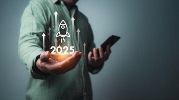 Businessman using smartphone with rocket icon and text 2025 for fast start up business, Startup business 2025 concept, Strategic planning and business success, target, stock market, business growth. photo