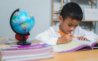 Education, Childhood, People, Homework and school concept. Student boy with book writing to notebook at home, Student learning study reading book while sitting at home. photo