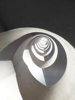 Cement spiral staircase see from the bottom up in an old building from the 90s. The light and shadow are clear and there is a perfect difference feeling of weightlessness with beautiful architecture photo