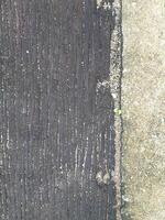 There were cracks in the road and there were two small grass plants. The cement floor was cracked, showing rocks and sand that were different in color and shape, creating strange new patterns. photo