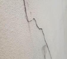 The cracks on the cream-colored concrete wall are long lines like mountains. The surface of the concrete is clearly visible, giving an unusual feeling. photo