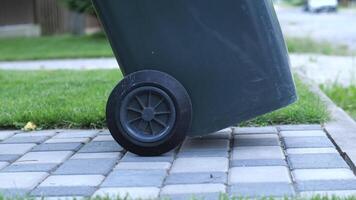 man rolls a trash can from his plot of land onto the street. Waste removal video
