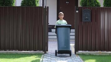 Garbage collector garbage removal from a private house. boy rolls out trash can video