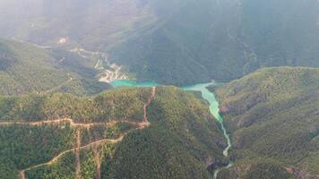 Experience a mesmerizing view of a winding turquoise river flowing through verdant mountains and valleys, capturing the breathtaking natural scenery from above video