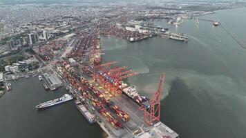 Drone films the seaport at sunset, highlighting crane operations with container ships. The crane moves containers between the dock and container ship, illustrating essential maritime logistics video