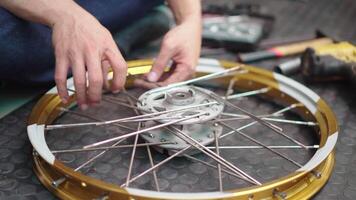 mechanic man work in garage , process of attaching the rim to the hub using spokes and nipples as fasteners, Repair or maintenance concept video