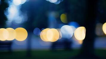 The bokeh lights in the city park at night evoke a sense of nostalgia reminiscent of fireflies on a summer evening and adding a touch of enchantment to the scene. Light leaks. video