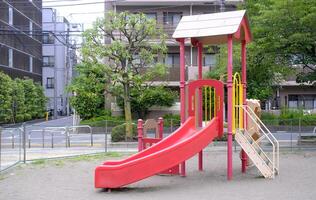 Red joyful slide for child and kids in Japanese residential playground photo
