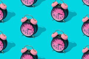 Trendy sunlight pattern made with pink and black retro alarm clock on bright blue background. Minimal time concept. photo