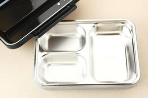 Empty Stainless Lunch box with compartments on wooden background photo