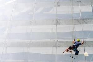 Window washer works on the wall of a glass building. photo