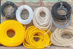 A bunch of different colored pipes are hanging on a wall. The yellow pipe is the most prominent photo
