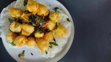 Tahu goreng cripsy, or crispy fried tofu, is one type of snack in Indonesia. With orange leaf on a white plate photo