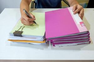 Man manager signing on accounting paper with stack file photo