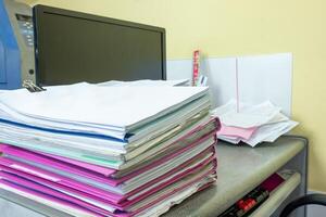Stack of accounting documents with computer screen on desk photo