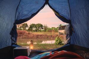 View from inside of tent with relaxing and campfire near swamp photo