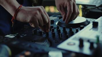 DJ carefully twisting the knobs of the mixer console during the live set. Musician is changing the settings of the controller with the hands close up video