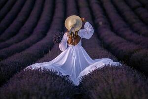 Woman Lavender Field Dress - A woman in a white dress and straw hat stands in a field of lavender. photo