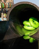 Waterpark Slides Tubes - Close-up view of green inflatable tubes inside a dark waterslide at a waterpark. photo