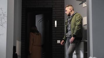 Man watching a woman leave through a doorway, The scene captures a moment of departure, with the man appearing contemplative as he gazes at the woman in a beige coat video