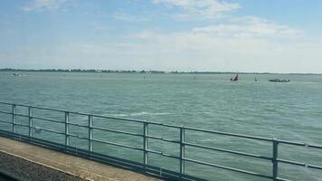 View from a bridge overlooking the Venetian lagoon, A peaceful scene captured from a bridge overlooking the Venetian lagoon, where the calm waters stretch out under a clear blue sky video