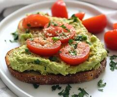 Avocado hummus toast topped with fresh tomatoes on a white plate photo