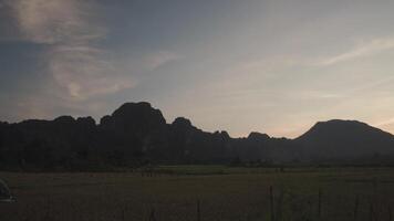 A powered parachute at Vang Vieng, Laos during sunset with a backdrop of karst mountains video