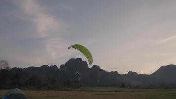 A powered parachute at Vang Vieng, Laos during sunset with a backdrop of karst mountains video