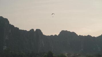 A powered parachute at Vang Vieng, Laos during sunset with a backdrop of karst mountains video