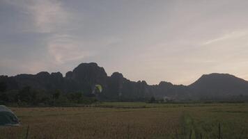 A powered parachute at Vang Vieng, Laos during sunset with a backdrop of karst mountains video
