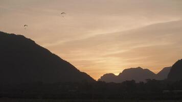 A powered parachute at Vang Vieng, Laos during sunset with a backdrop of karst mountains video