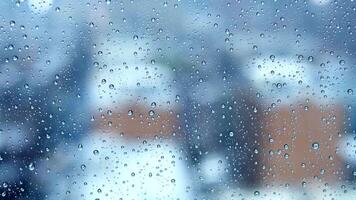Raindrops on a glass window, creating an abstract and blurry background with a view of the cityscape video